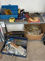 Overall view of shelf with tool trays, hammers, clamp, sanding block, cords and hardware