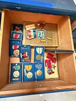 Drawer showing Bronze Star in case, five boxed WWII medals, loose ribbons, presentation album