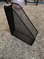 Side view of black metal mesh magazine holder