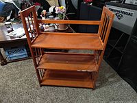 Front view of honey wood bookcase showing three shelves and open slat sides