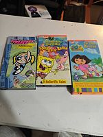 Front view of three VHS cases: Powerpuff Girls, SpongeBob SquarePants, Dora the Explorer