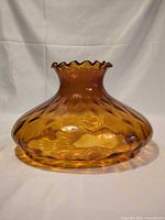 Overall view of amber glass lamp shade showing ruffled rim and swirl texture