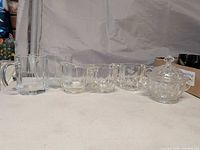 Entire set of clear glass mugs, creamers, sugar bowl lined up