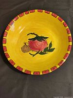 Top view of yellow ceramic serving bowl with tomato, onion artwork and red patterned rim