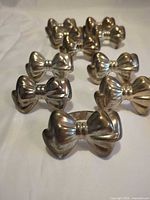 Ten silver-tone bowtie napkin rings arranged on fabric background