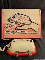 Massager in front of original box showing product name and graphics