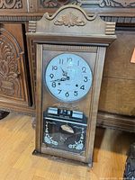 Full front view of Frontier wooden pendulum wall clock with door closed