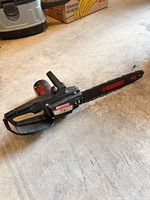 full view of Mastercraft corded chainsaw lying on concrete floor