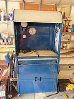 Workbench front with tambour door open showing pegboard, lights, pull-out surface, drawer and lower cabinet