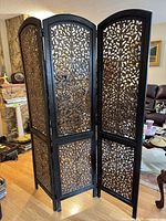 Full view of three-panel carved wood room divider standing open