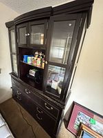 Front view of entire dark brown china cabinet showing glass doors, open center display shelf, and lower drawers