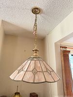 Full view of pendant light hanging from ceiling showing shade, chain, canopy