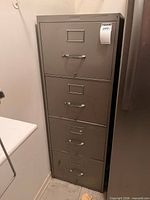 Front view of four-drawer metal file cabinet showing handles and label holders