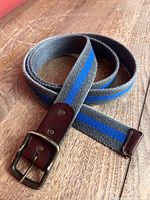 Entire coiled belt showing grey canvas, blue stripe, leather tip, and brass-tone buckle