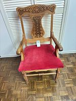Front view of carved wood armchair with red seat