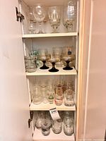 Cabinet view of three shelves filled with varied glassware