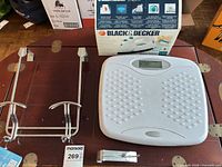 Overview showing bathroom scale, boxed iron, chrome over-door rack, small light accessory on wooden surface