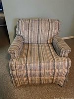 Front view of striped upholstered armchair showing arms, cushion and skirt