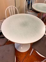 Top view of round speckled laminate table with chairs and cushions visible