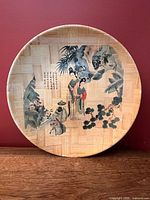 Front view of the round bamboo wall plate showing full artwork and weave