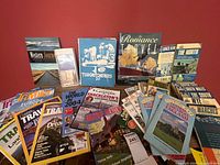 Overall lot showing hardcovers, yearbook, maps and magazines spread on table