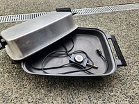 Skillet open showing nonstick interior, thermostat cord and aluminum lid