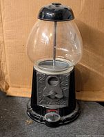 Front view of black gumball machine showing clear globe, coin mechanism, Continental logo