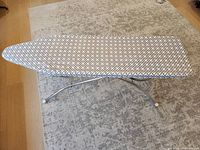 Full view of ironing board unfolded on floor rug