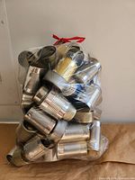 Full view of sealed plastic bag filled with empty tin cans