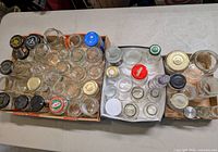 Top view of three cartons filled with assorted clear glass jars and bottles with various lids
