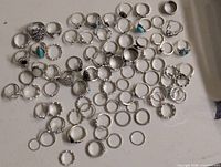 Overview of entire assortment of silver-tone rings spread on table