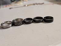 Five rings laid out side-by-side showing design and finishes