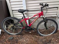 Left side full view of red Norco Detonator bike leaning against wall