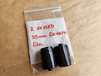 Front view of two unused 35 mm film cartridges in bag with handwritten note