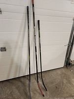 Three junior hockey sticks leaning against wall