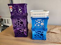 Stack of three purple and two blue storage crates with two white trays on top