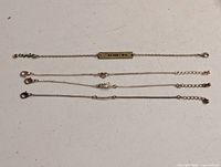 Four chain bracelets laid flat showing charms and clasps