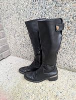 Side view of both black knee-high boots showing zipper, strap, and overall condition