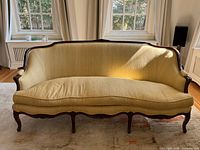 Front view of yellow silk upholstered Louis XV style settee showing carved wood frame and serpentine apron