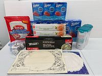 Full lot showing all packaged items: Ziploc boxes, Saran sheets, Titan wrap, PC bags, container, placemats, doilies