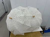 overview of both lace parasols folded open showing lace pattern and wood handles