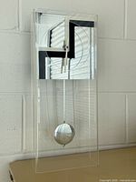 Full view of lucite clock showing case, face and pendulum