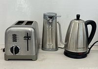 Three stainless appliances: kettle, toaster, can opener
