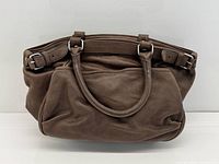 Front view of brown leather Vanessa Bruno handbag showing dual rolled handles and buckle accents