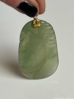 Front view showing carved jade leaf design and gold-tone bail