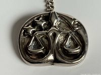 Front view of sterling Libra pendant showing scales and stars relief