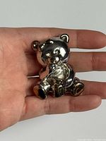 Front view of sterling silver teddy bear pendant brooch in hand for scale