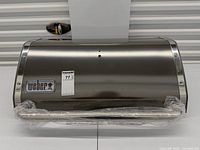 front view of stainless Weber grill lid showing logo badge and handle