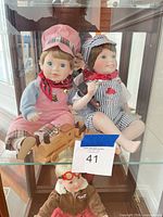 Front view of two porcelain boy dolls seated with wooden train