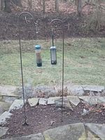 Full view of metal double-hook stand installed in garden bed with both feeders hanging